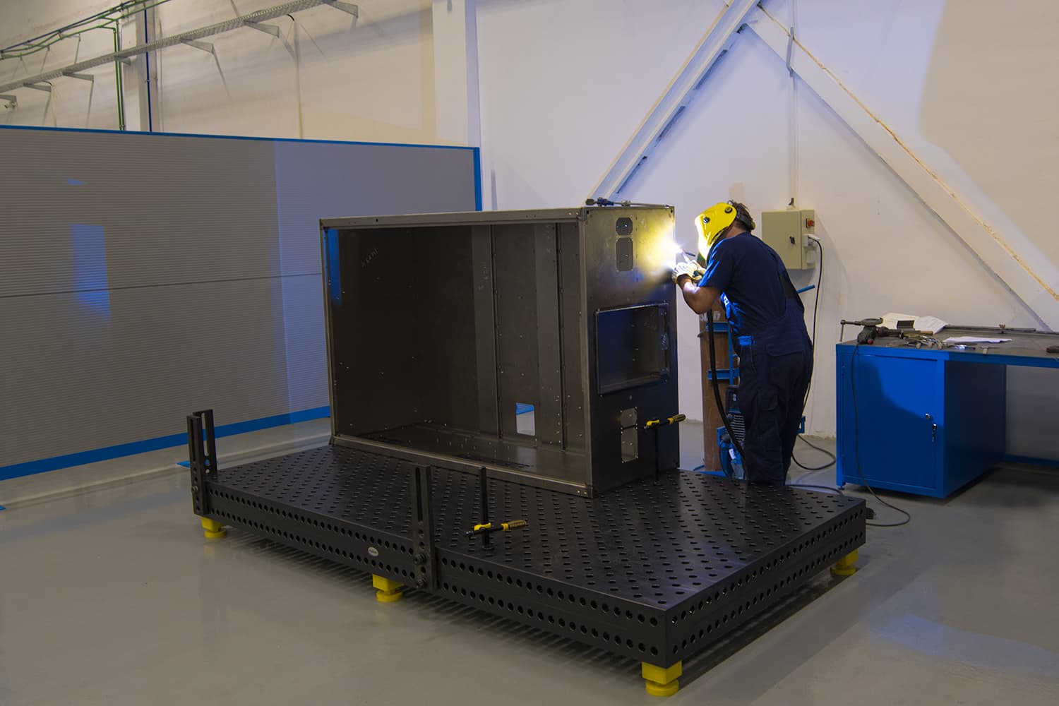 Welder joining a sheet metal enclosure on a fixture welding table at the Yambol plant