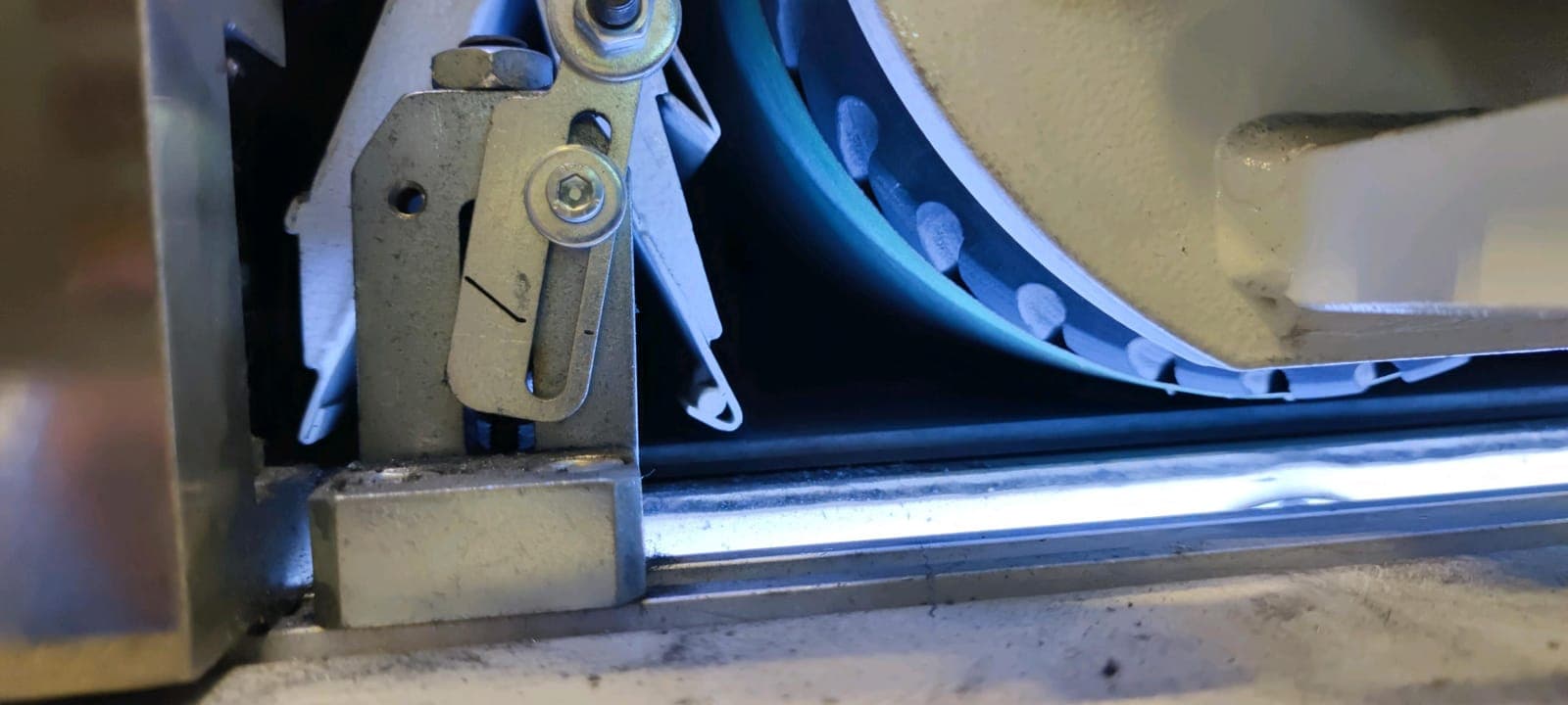 Abrasive belt running over its drum in the belt station